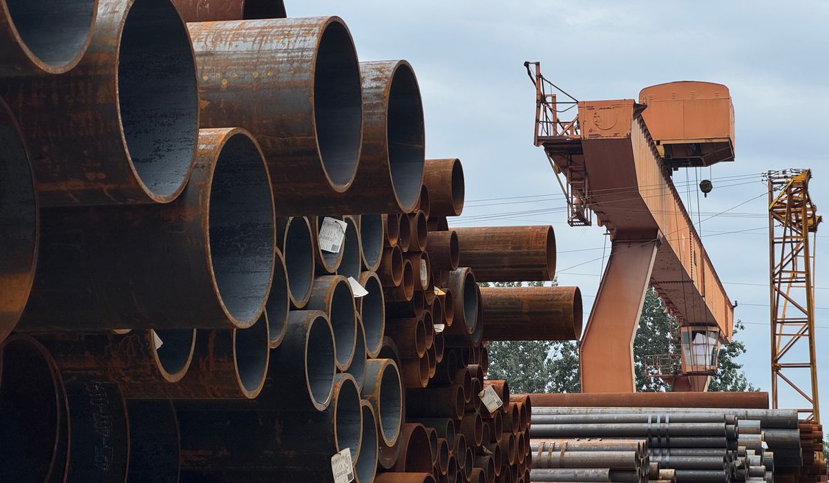 Stacked steel pipes in a supplier stockyard with overhead gantry crane in India